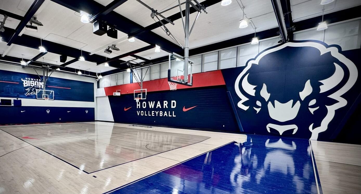 Completed hardwood gymnasium floor renovation at Howard University featuring navy blue and red court markings, Howard Bison logos, and custom HU center court design