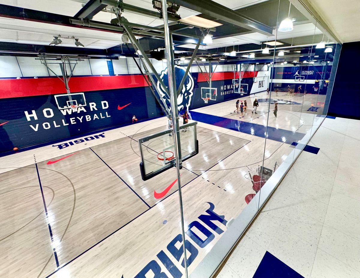 Completed hardwood gymnasium floor renovation at Howard University featuring navy blue and red court markings, Howard Bison logos, and custom HU center court design