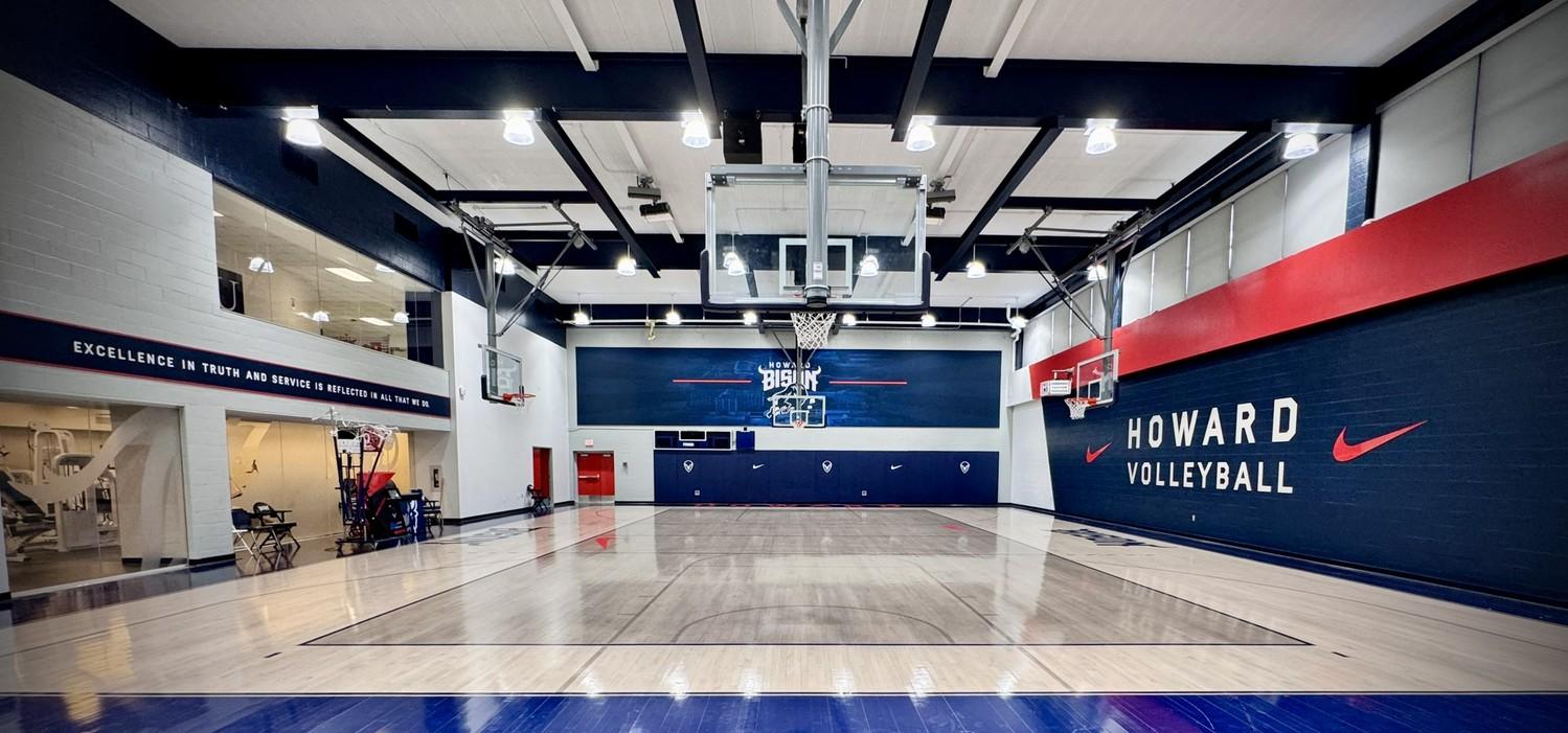 Completed hardwood gymnasium floor renovation at Howard University featuring navy blue and red court markings, Howard Bison logos, branding, and custom HU center court design