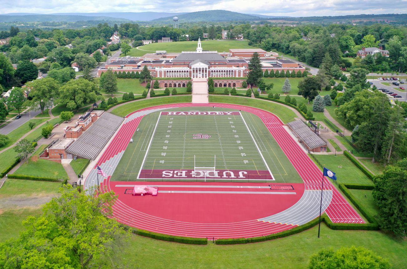 Completed outdoor track and field installation at John Handley High School in Winchester Virginia featuring crimson red running surface, multi-lane competition track, and green artificial turf football field