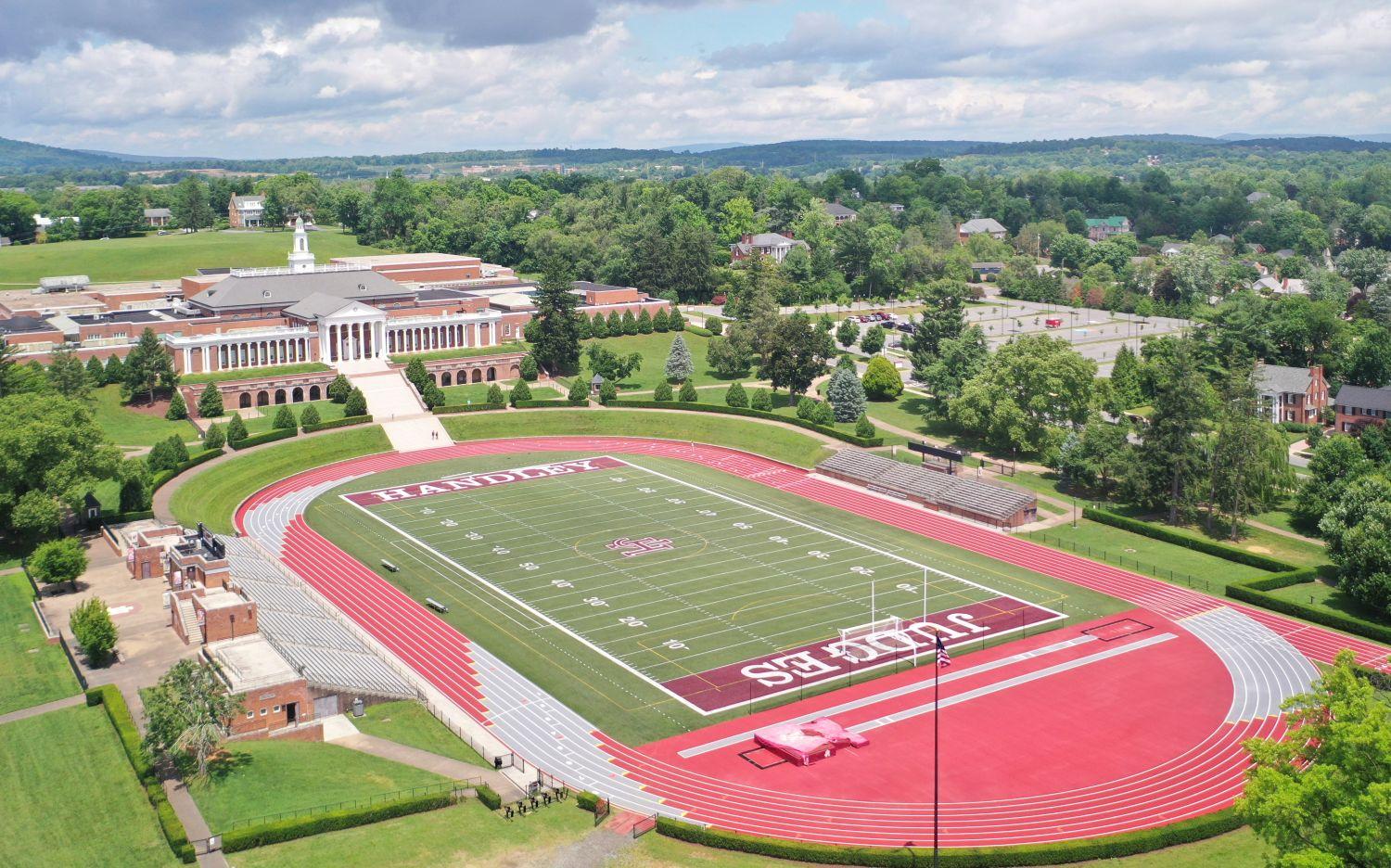 Completed outdoor track and field installation at John Handley High School in Winchester Virginia featuring crimson red running surface, multi-lane competition track, and green artificial turf football field