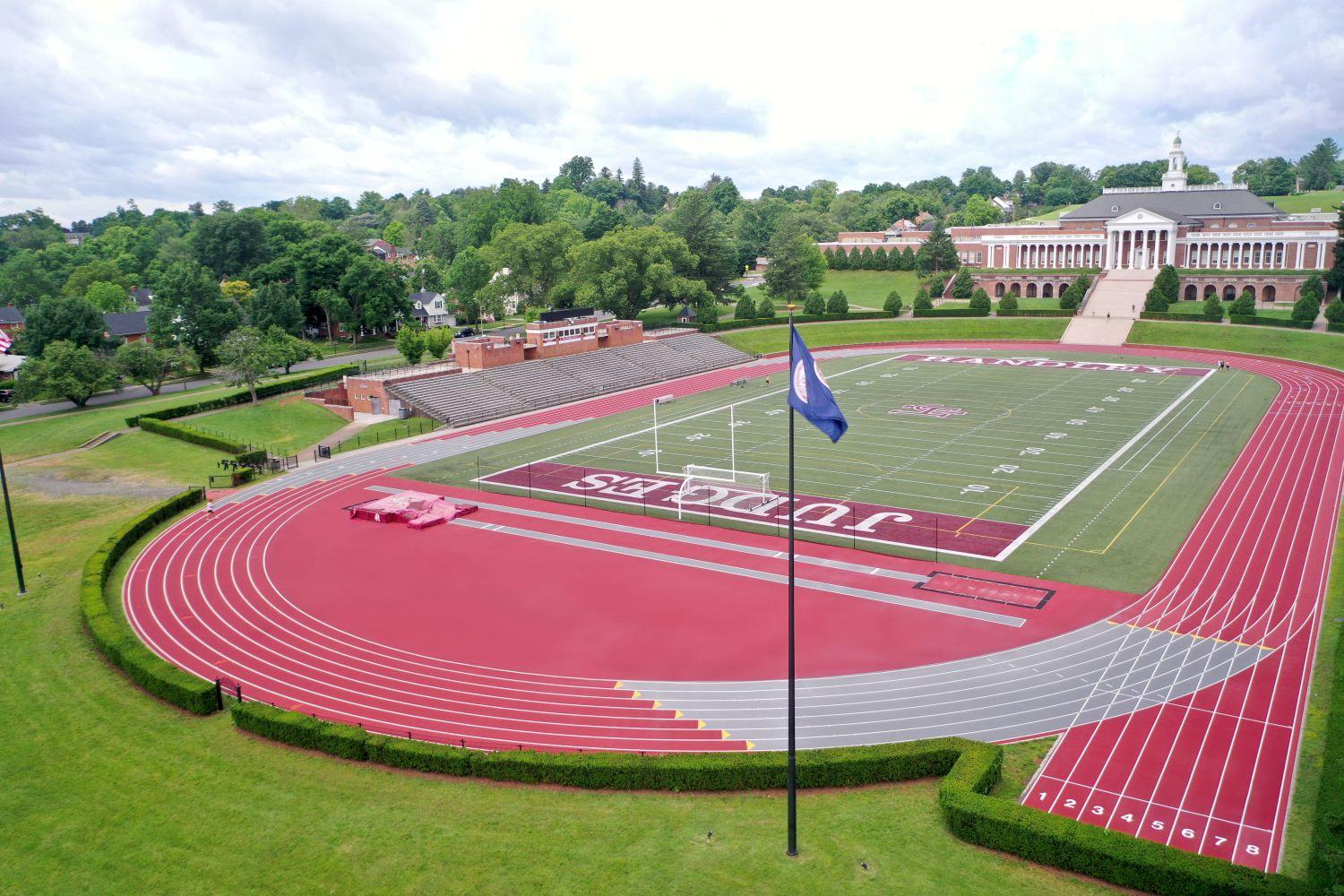 Completed outdoor track and field installation at John Handley High School in Winchester Virginia featuring crimson red running surface, multi-lane competition track, and green artificial turf football field