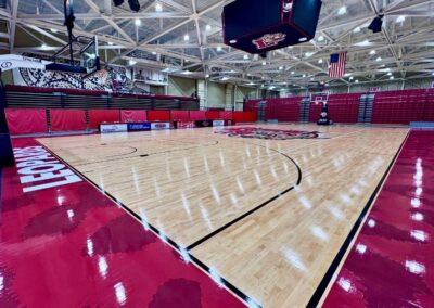 Completed hardwood gymnasium floor renovation at Lafayette College featuring crimson and black court markings, Lafayette Leopards logo center court, and custom leopard print out-of-bounds design