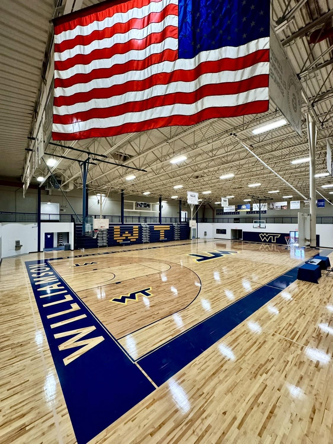 Completed hardwood gymnasium floor renovation at Williamson College of the Trades featuring navy blue court markings and WT logos