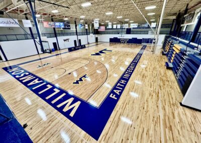 Completed hardwood gymnasium floor renovation at Williamson College of the Trades featuring navy blue court markings and WT logos