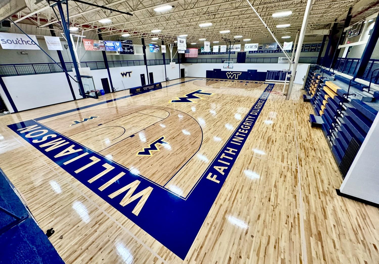 Completed hardwood gymnasium floor renovation at Williamson College of the Trades featuring navy blue court markings and WT logos