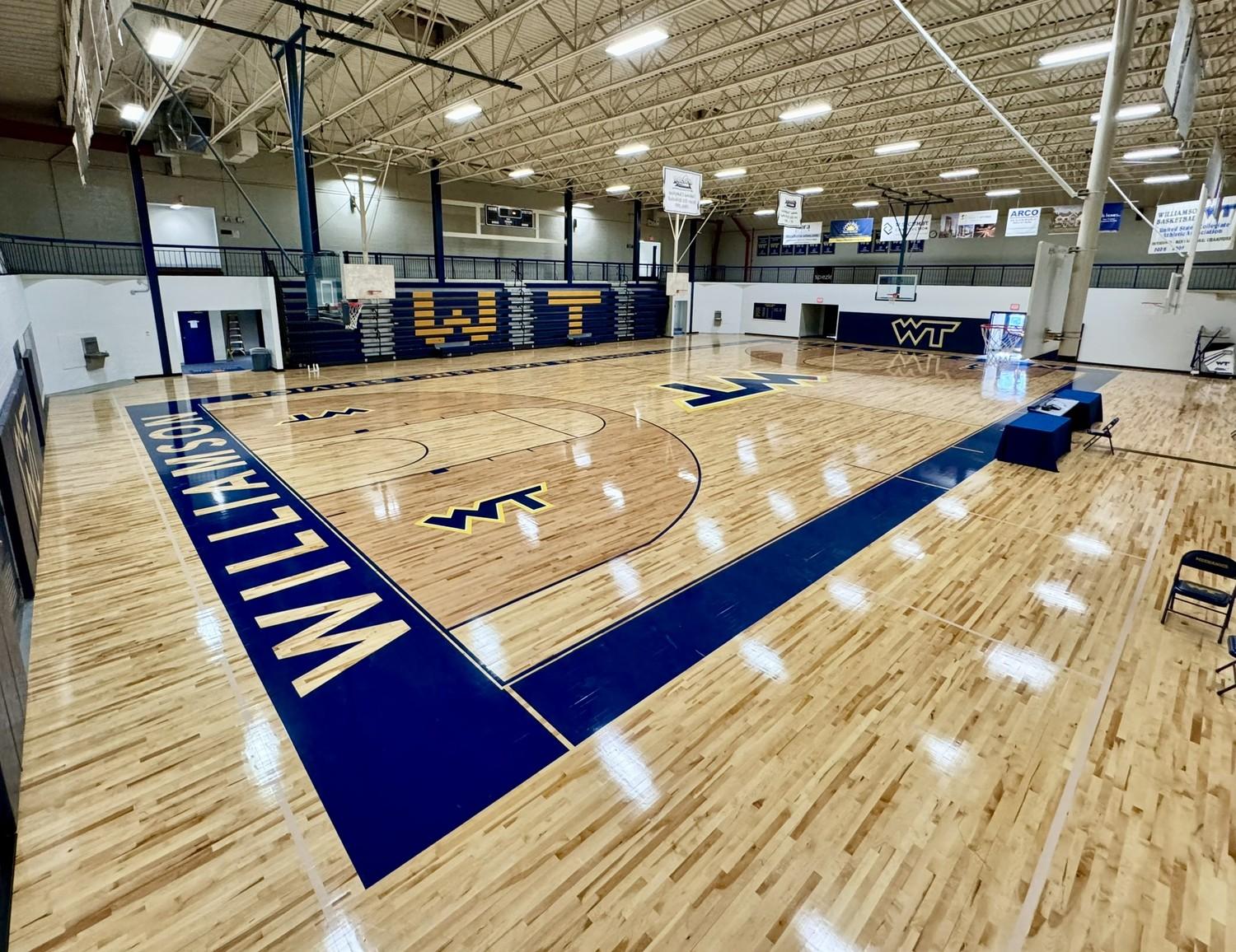 Completed hardwood gymnasium floor renovation at Williamson College of the Trades featuring navy blue court markings and WT logos