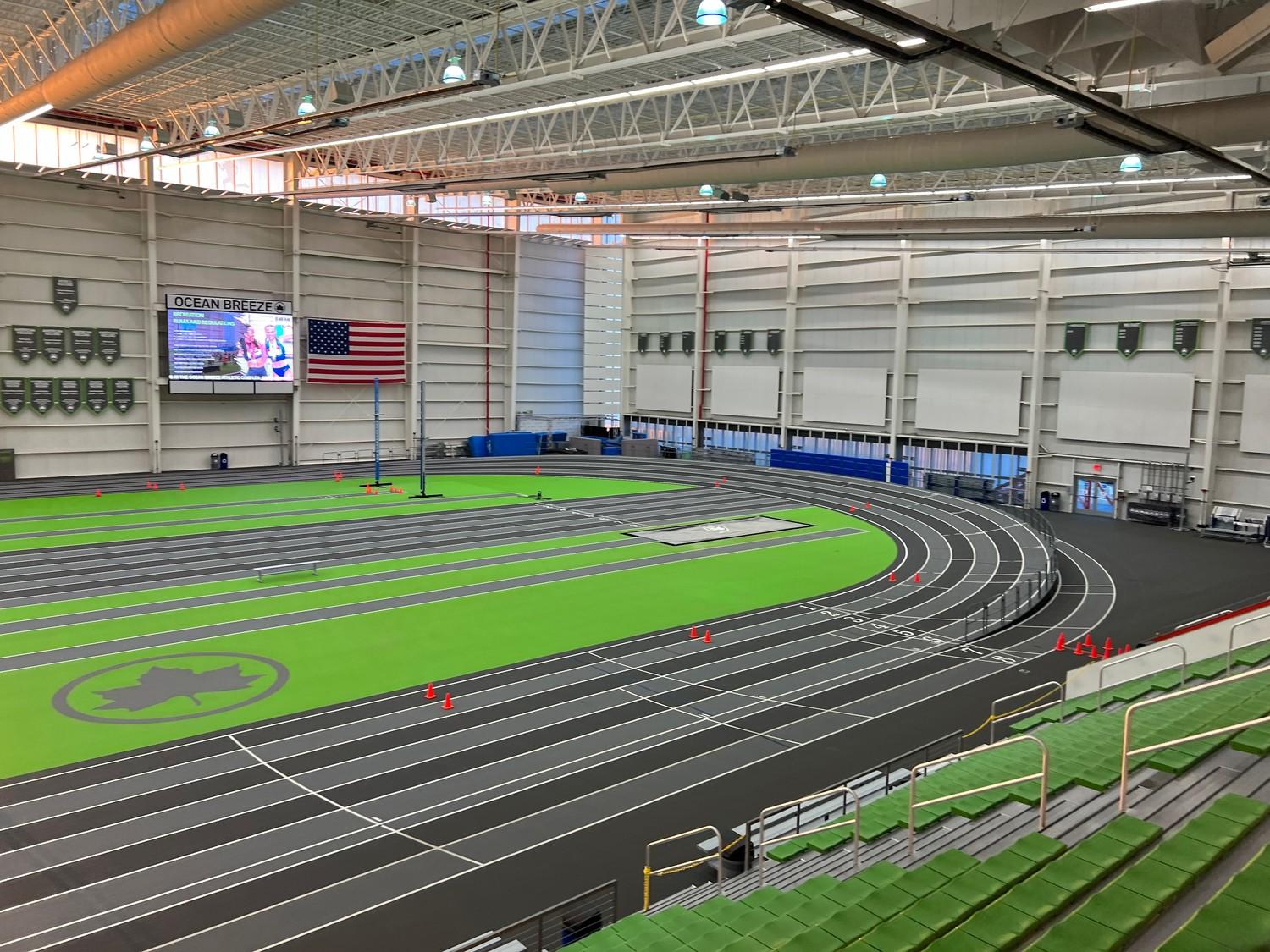 Completed indoor track and field installation at Ocean Breeze Athletic Complex in Staten Island featuring dark gray running surface, green infield turf, and multi-lane competition track