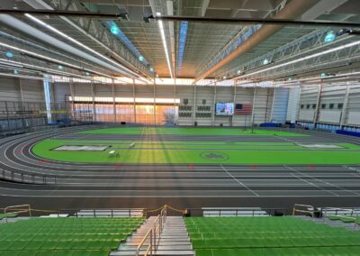 Completed indoor track and field installation at Ocean Breeze Athletic Complex in Staten Island featuring dark gray running surface, green infield turf, and multi-lane competition track