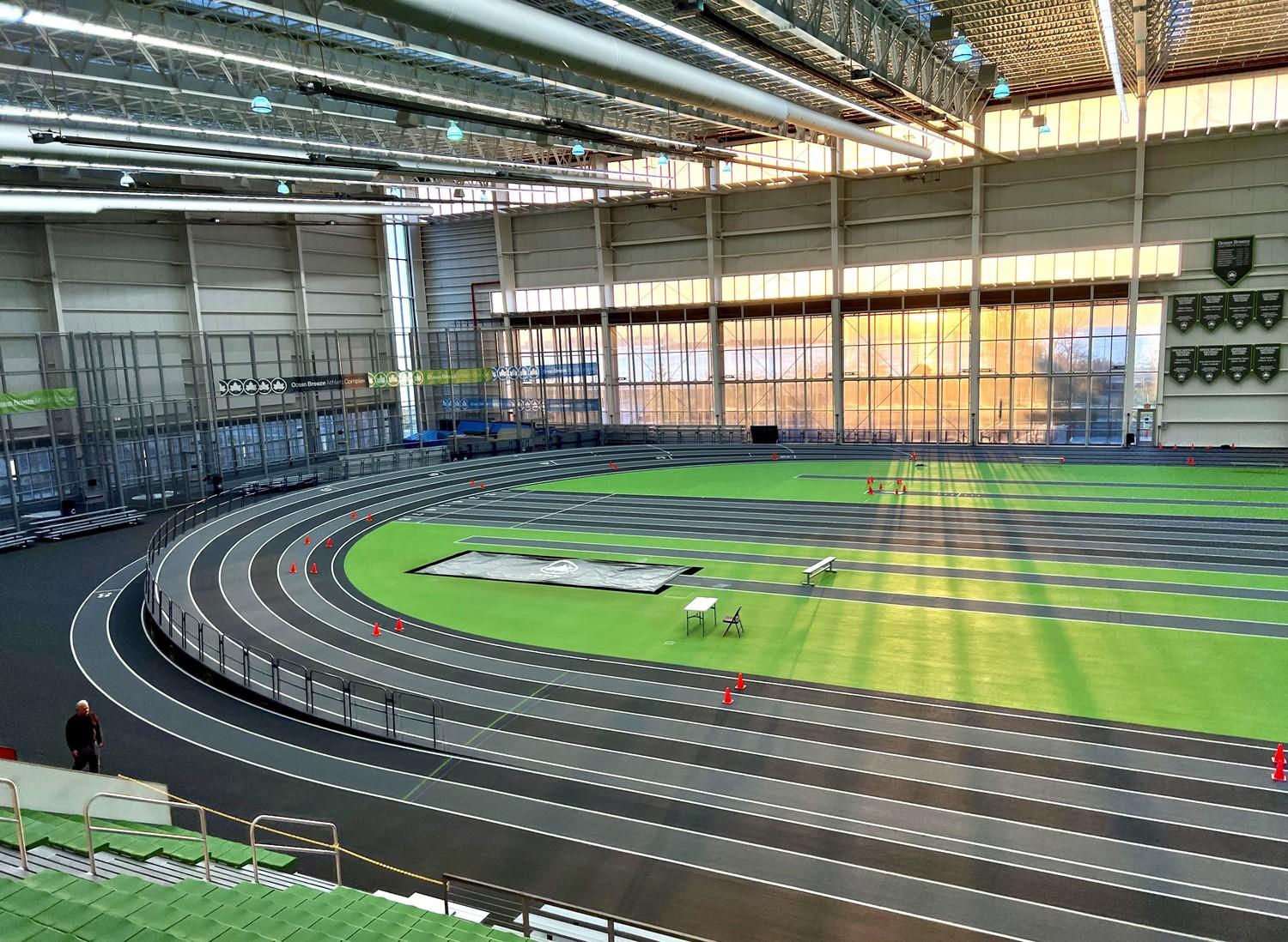 Completed indoor track and field installation at Ocean Breeze Athletic Complex in Staten Island featuring dark gray running surface, green infield turf, and multi-lane competition track