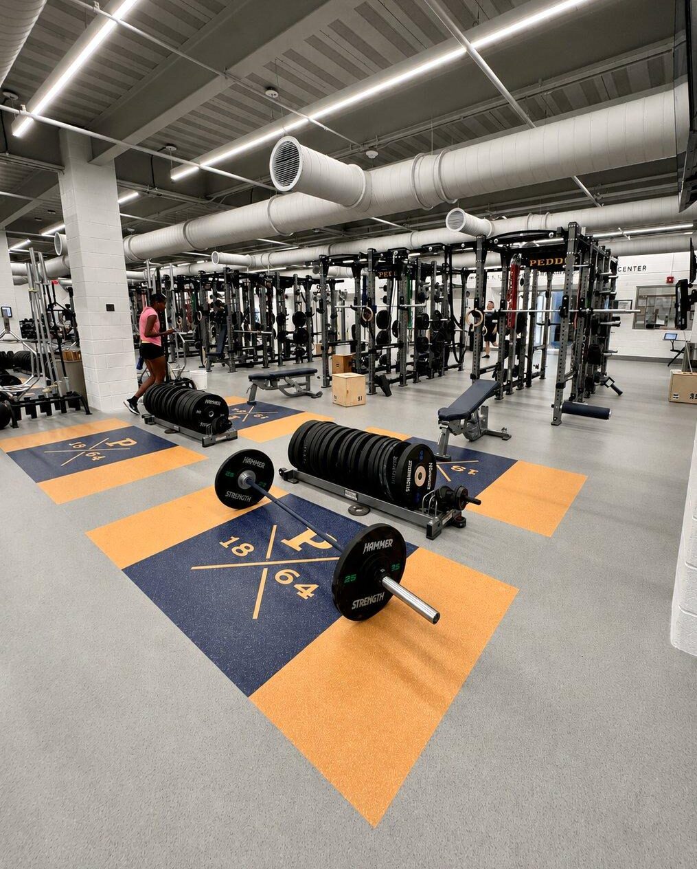 Full view of Peddie School performance weight room with rows of Hammer Strength power racks and custom flooring