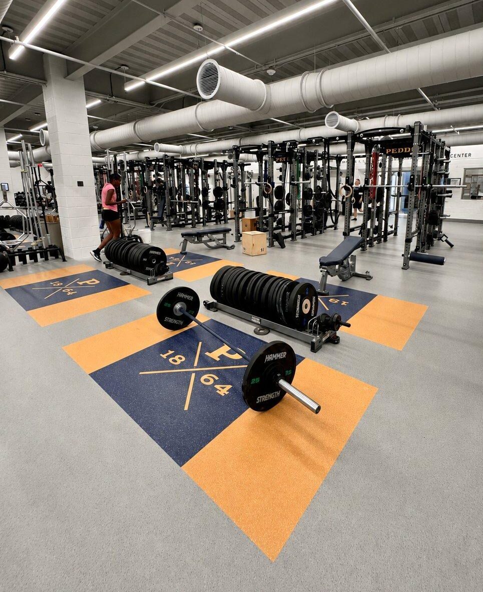 Custom branded rubber lifting platforms with plate storage trees in Peddie School athletic performance center weight room