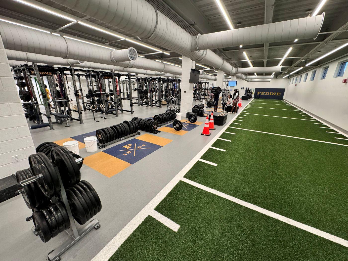 Hammer Strength barbell on custom navy and gold Peddie School branded lifting platform with power racks in athletic center weight room