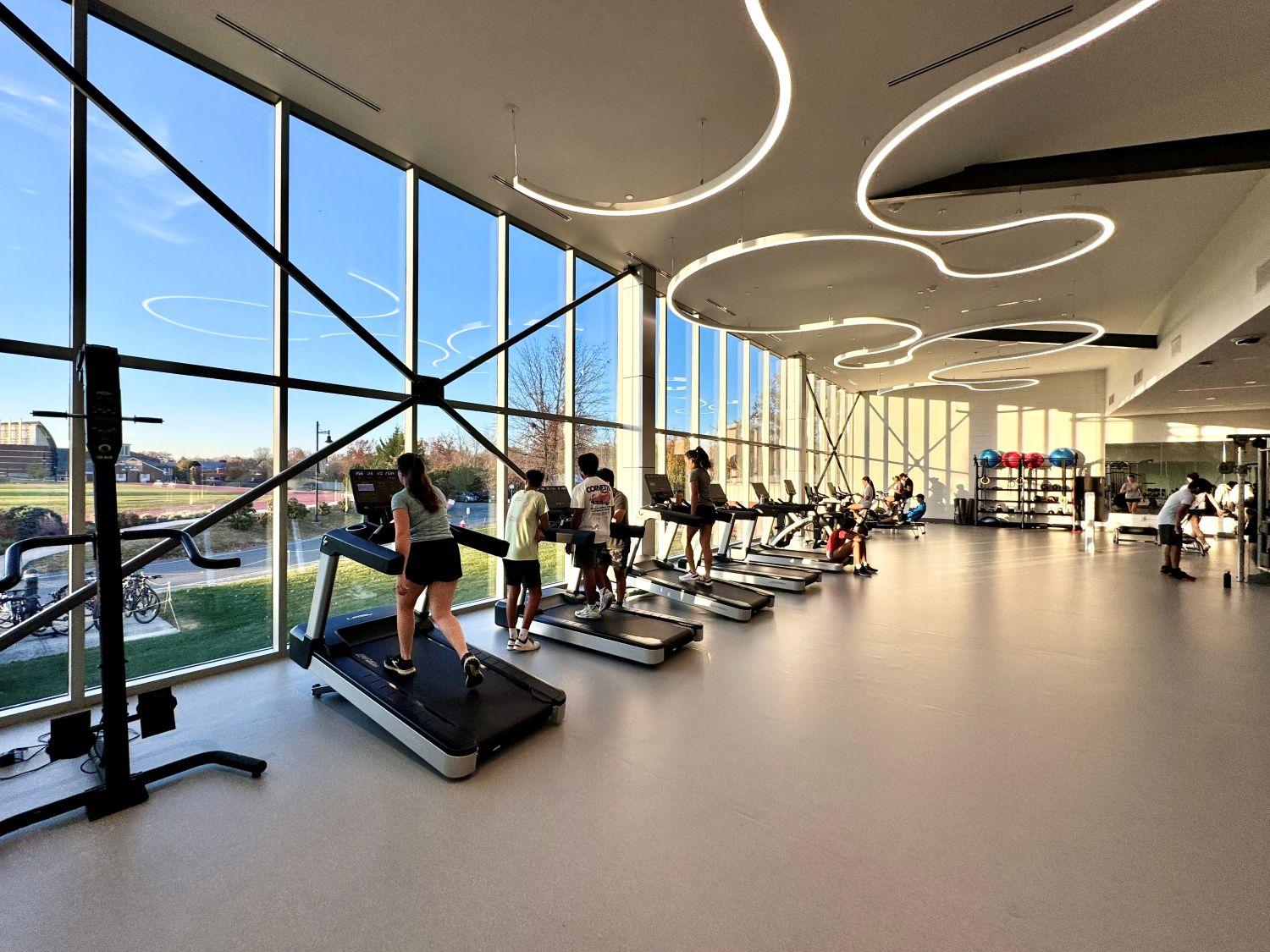 Cardio fitness floor at Peddie School with treadmills along a wall of floor-to-ceiling windows overlooking the campus