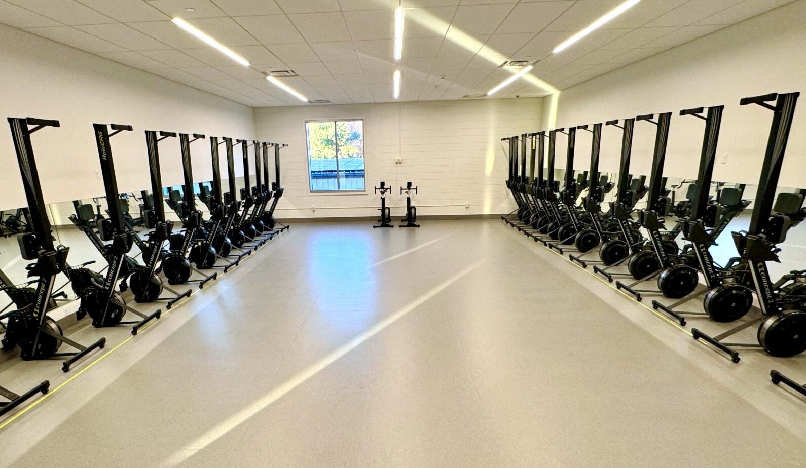 Rowing machine training room at Peddie School with two rows of ergometers facing floor-length mirrors