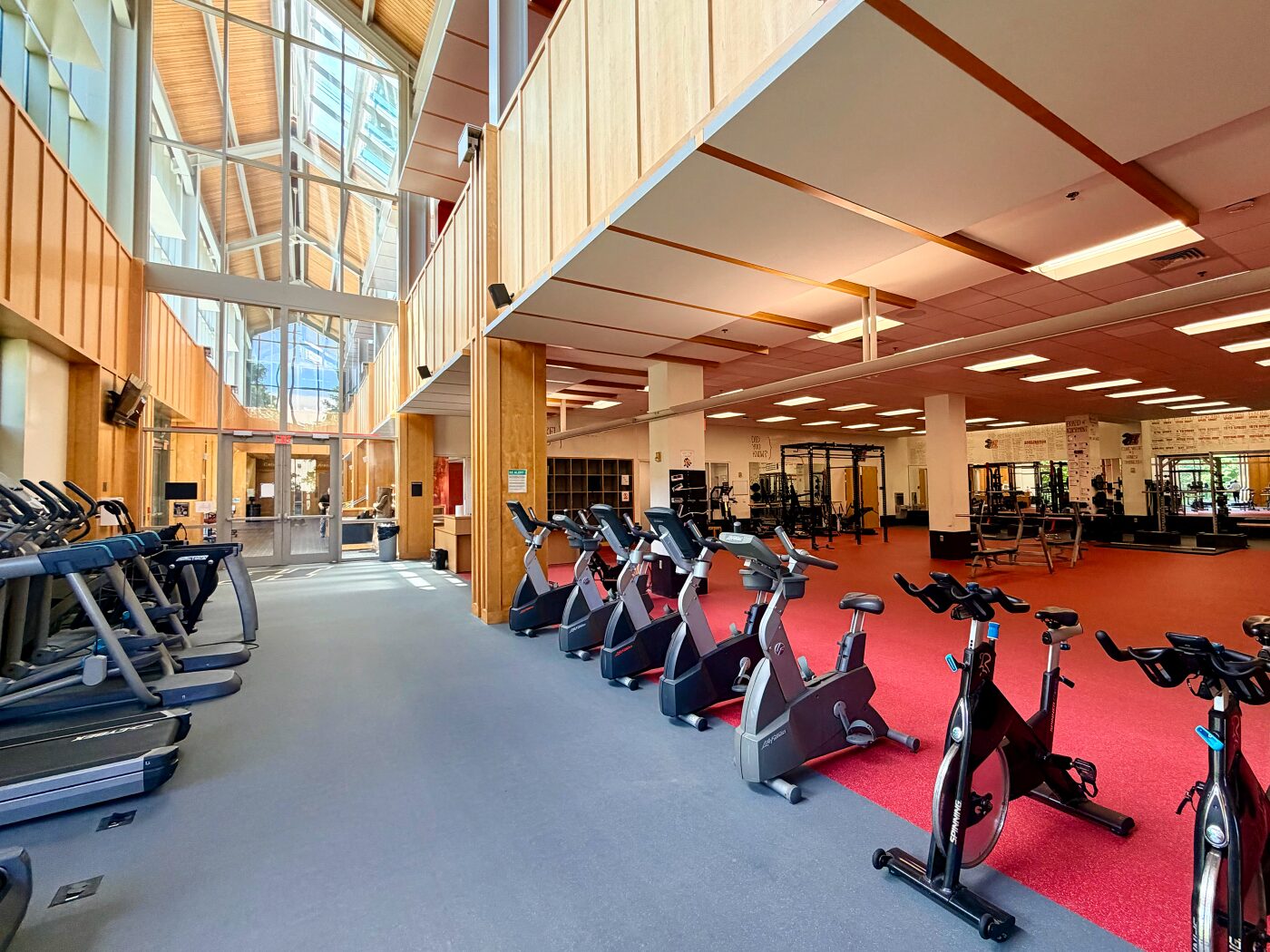 Gray Mondo Valor S rubber flooring in the Haverford College weight room featuring a water-jet cut black and white H logo inlay, with cardio equipment along the window wall.