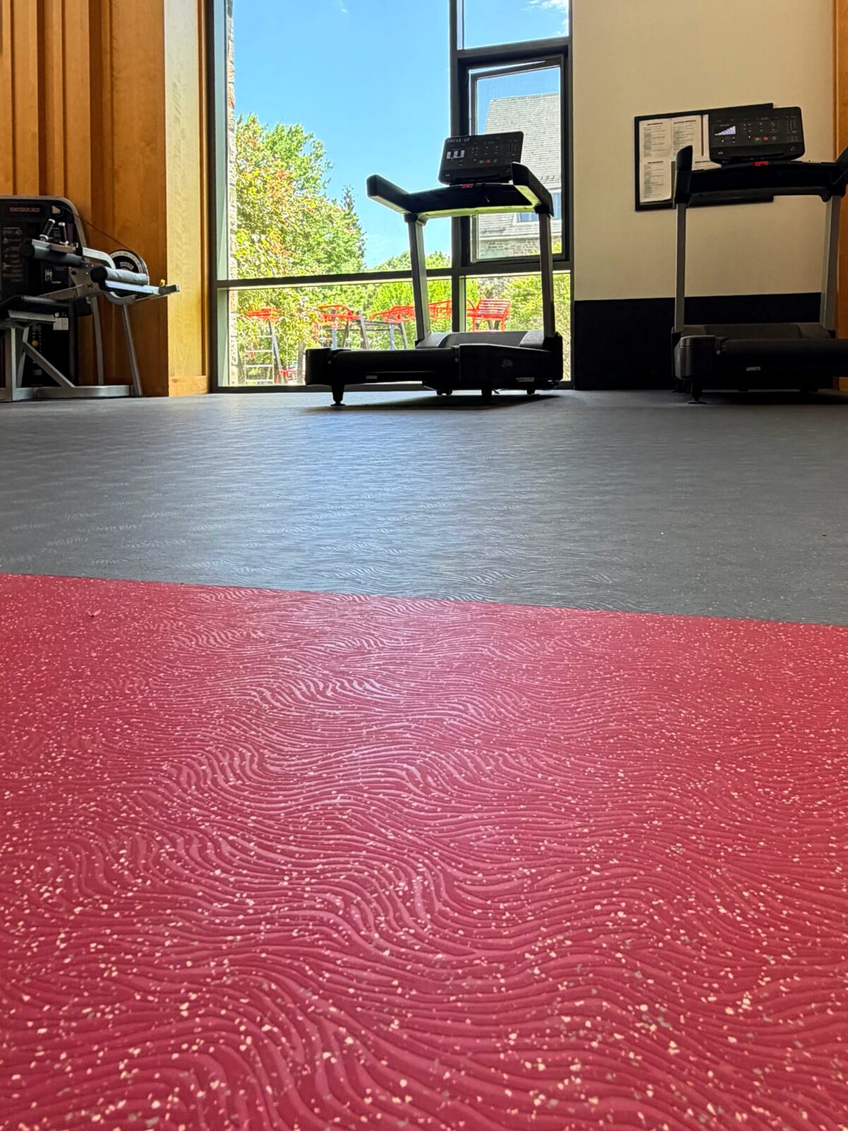 Vaulted-ceiling weight room at Haverford College with gray Mondo Valor S flooring in a wave pattern, treadmills and free-weight area with athletes training.