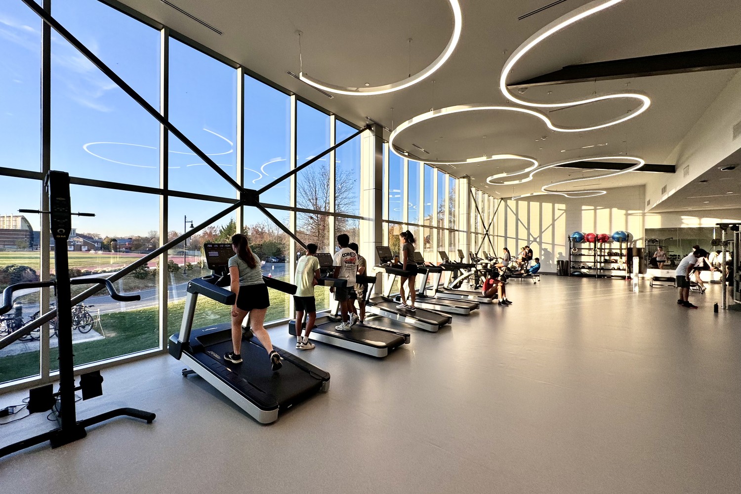 Cardio fitness floor at Peddie School with treadmills along a wall of floor-to-ceiling windows overlooking the campus
