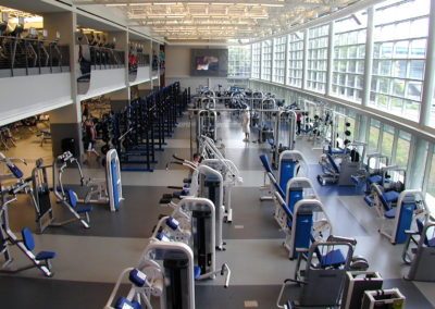 Penn State Recreation Center fitness floor with rows of strength machines and cardio equipment beneath a mezzanine level