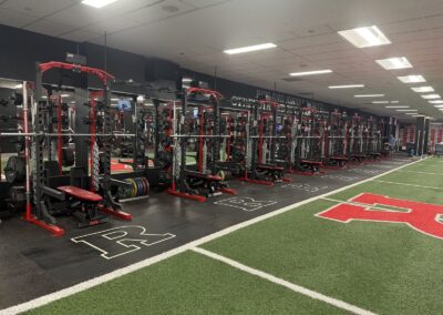 Row of strength racks with chains at Rutgers' Garutti Strength and Conditioning Center, opening directly onto the football practice field